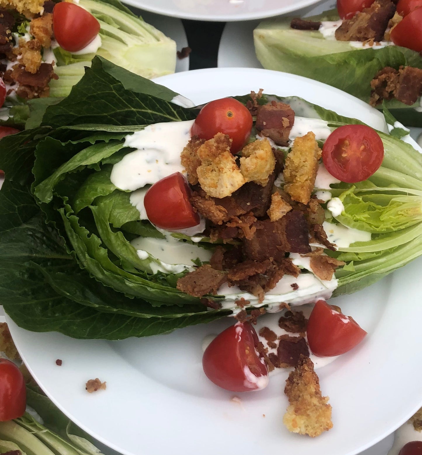 Wedge salad with tomatoes and croutons on a white plate.
