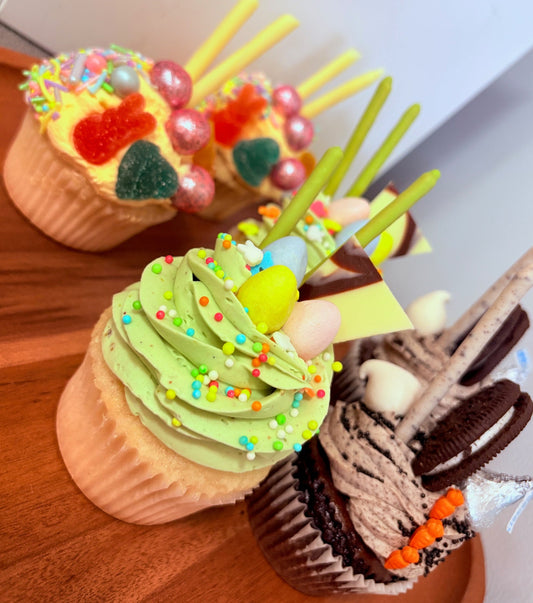 Six decorated cupcakes on a wooden surface with a white background