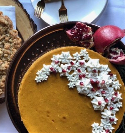 Pie on a table with decorative whipped cream and pomegranate seeds.