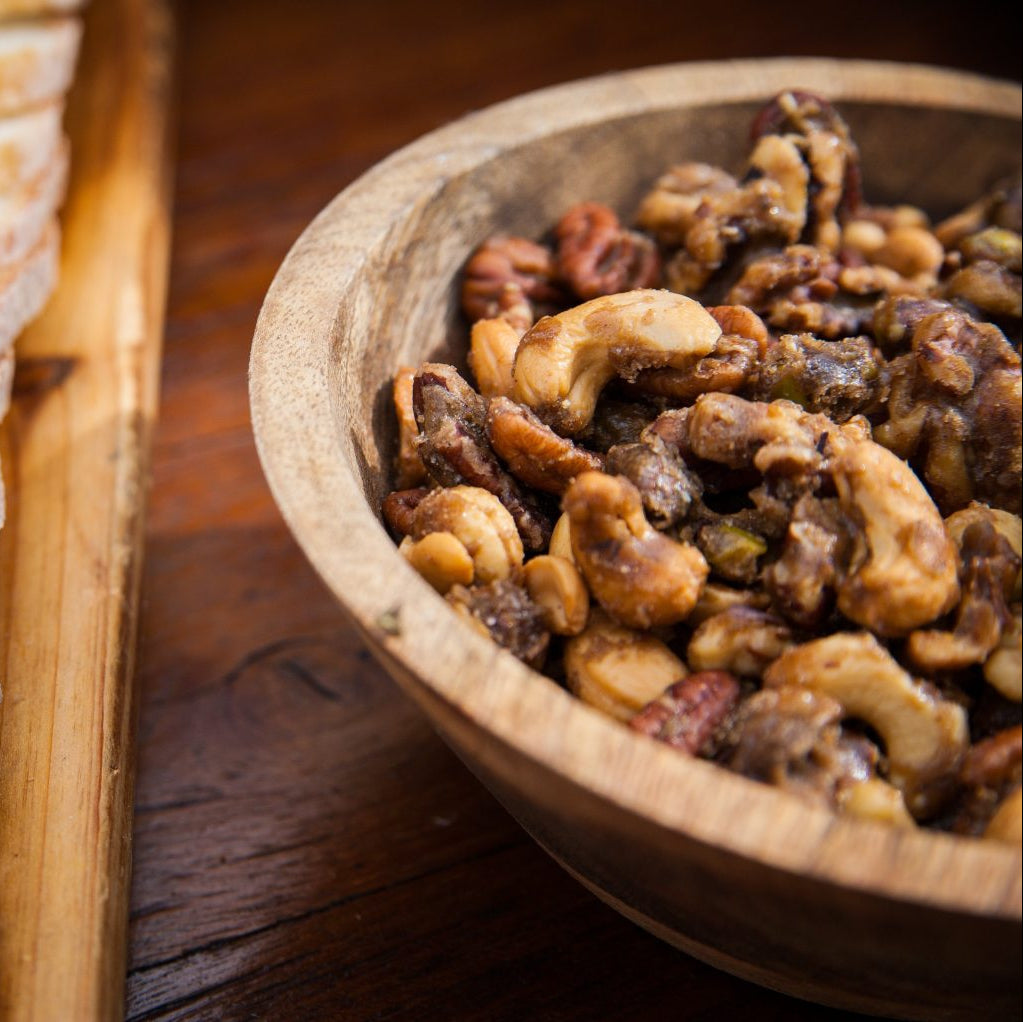 Bowl of nuts and dried fruits on a wooden surface.