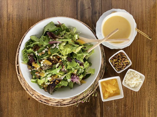 Bowl of salad with dressing, nuts, and cheese on a wooden table